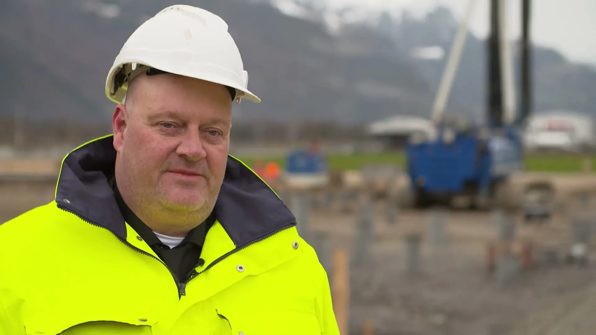 Christoph Pfister auf einer Baustelle mit Rammgerät im Hintergrund