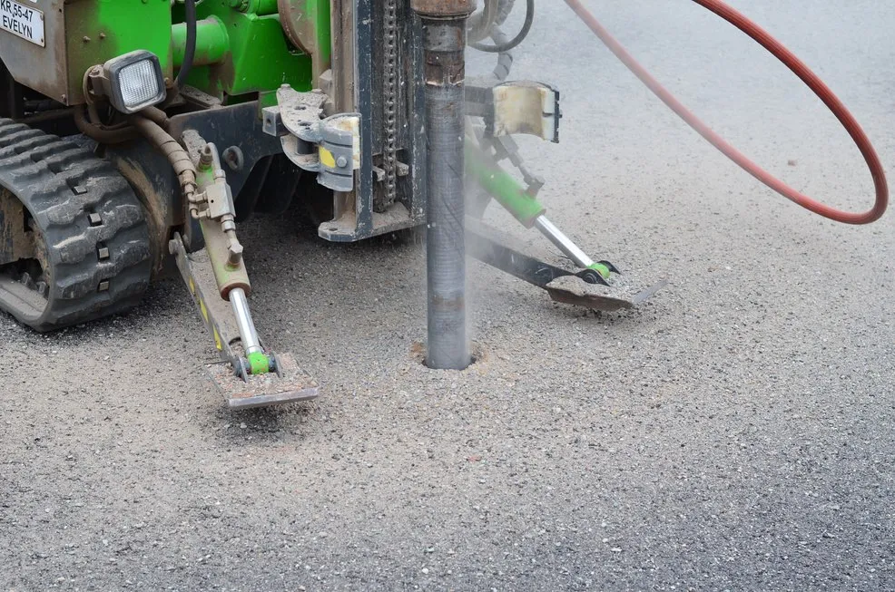 Eindrehen eines Schraubfundaments durch die Asphaltdecke eines Parkplatzes
